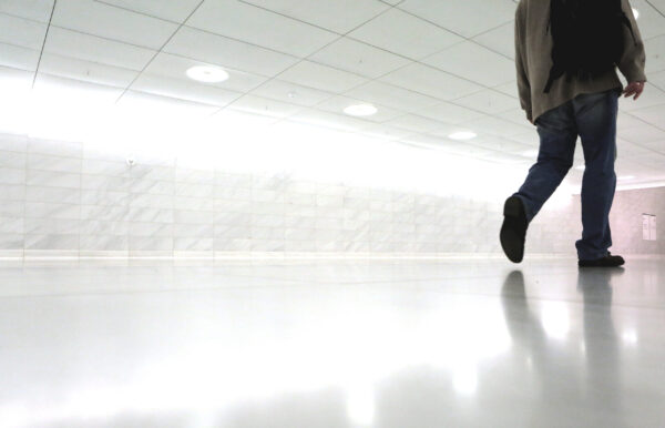 
	A businessman walking alone, with a bag on his shoulder, leaving an office, high lights with bright lightning
